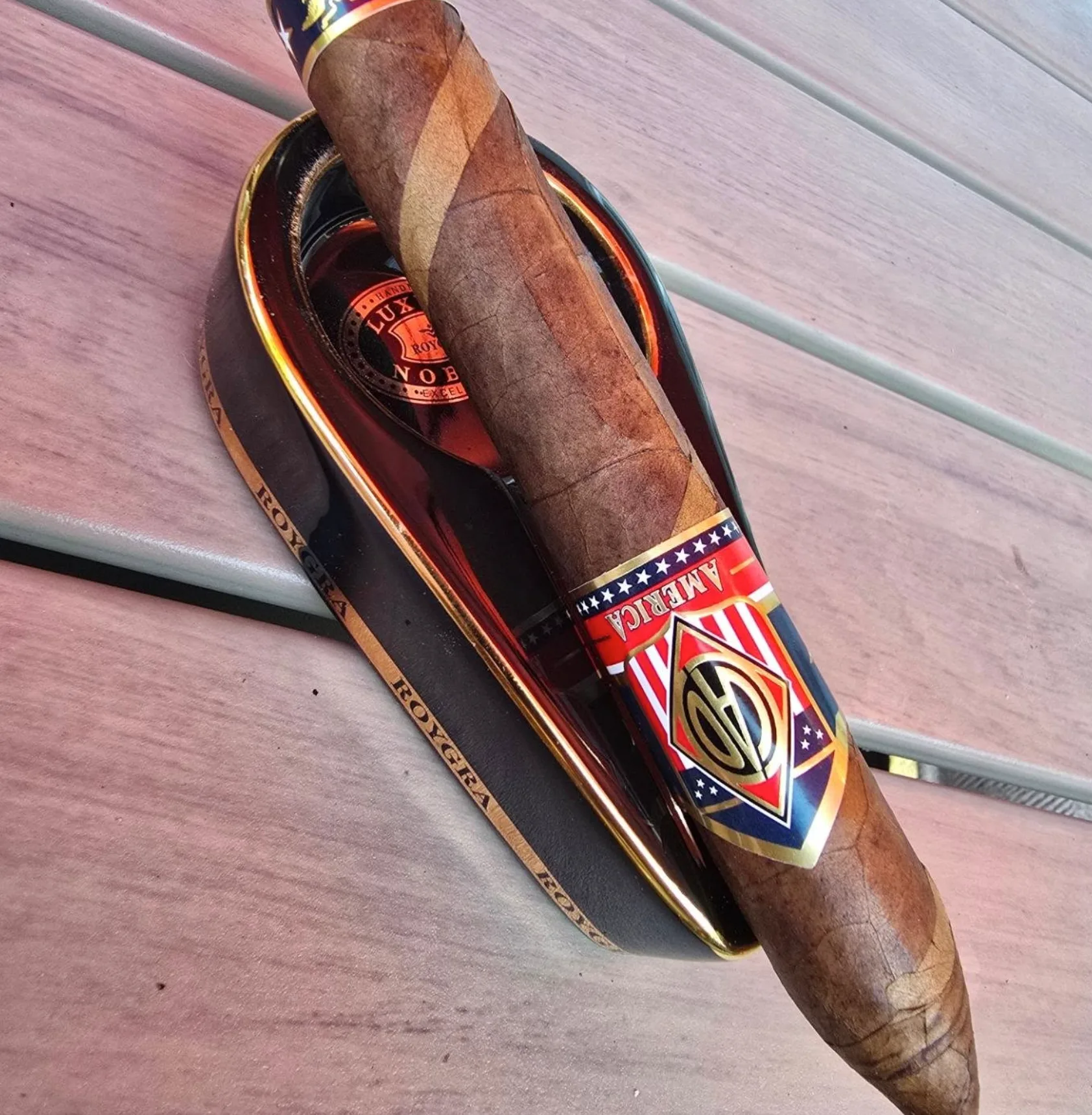 A barber-pole perfecto cigar with an America band resting in a black ashtray